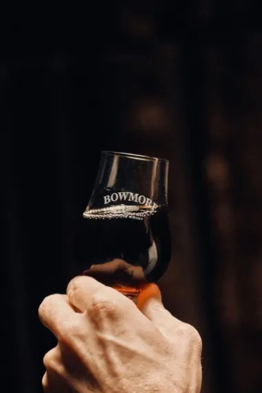 Hand holding up a glass of whisky.