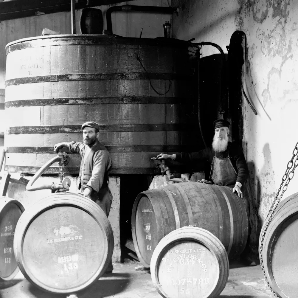 Two bearded men in Islay distillery by barrels.