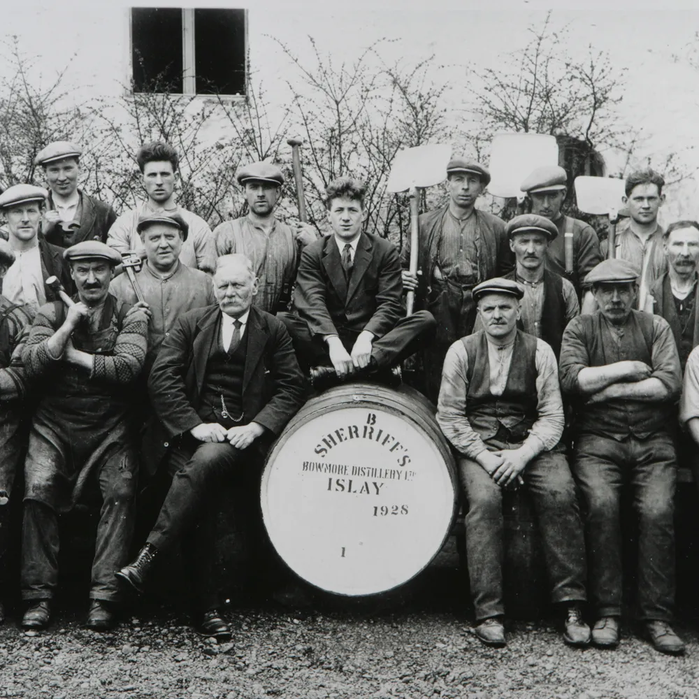 Group of men posed around a barrel.