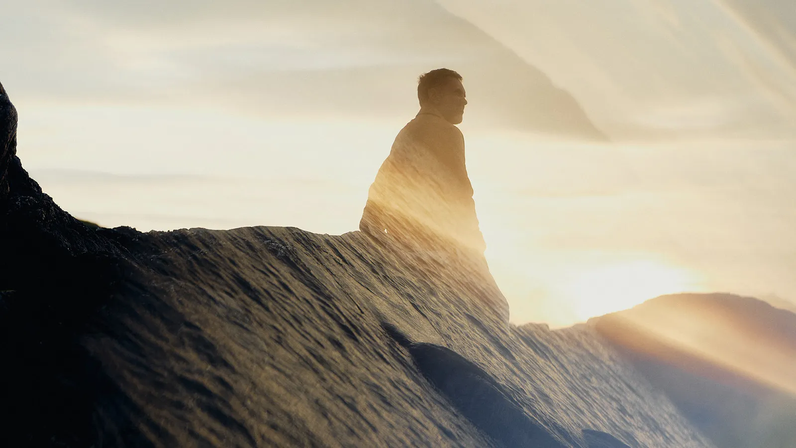 Person on rock edge wrapped in towel.