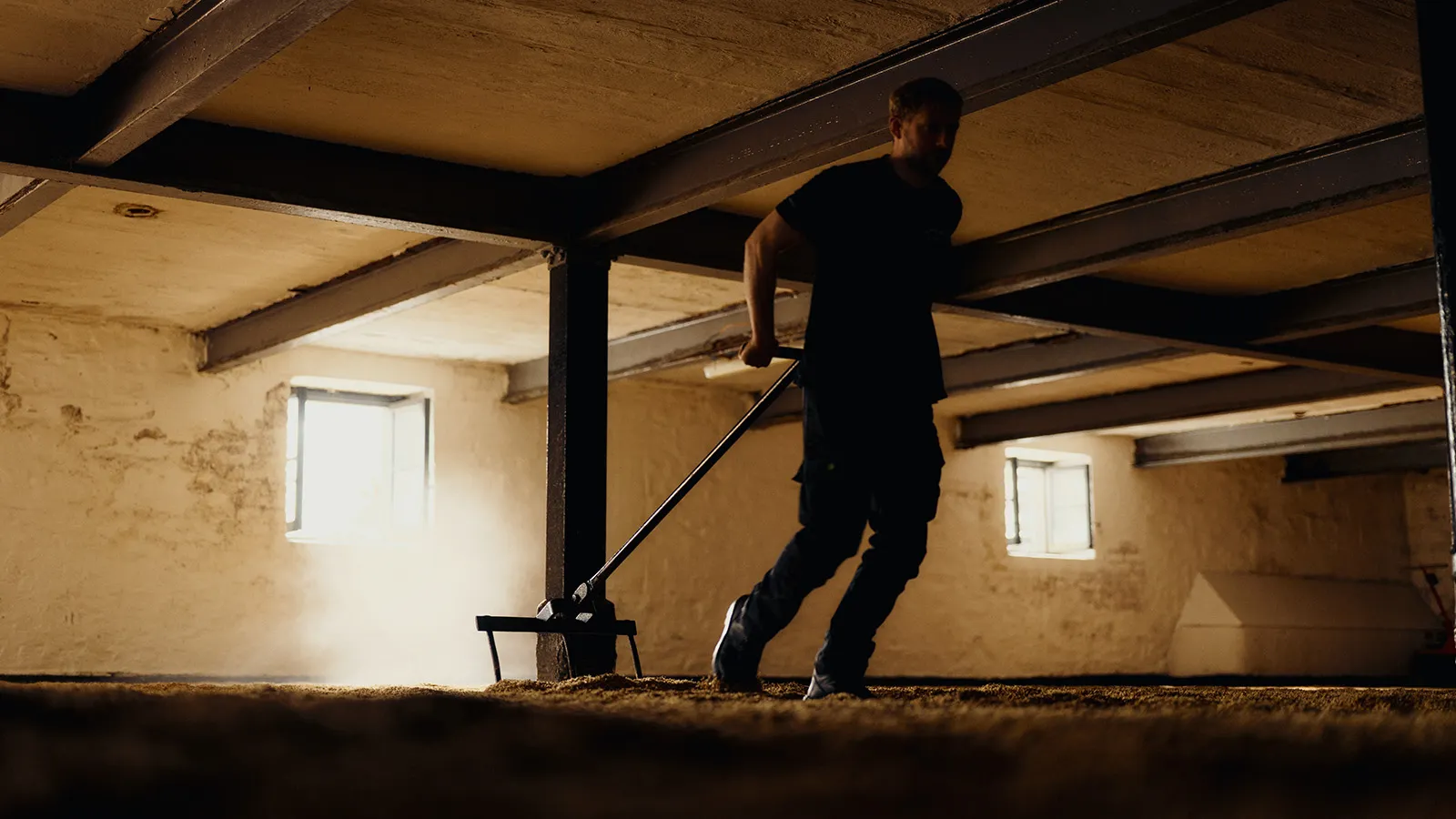 Man turning barley in barn.