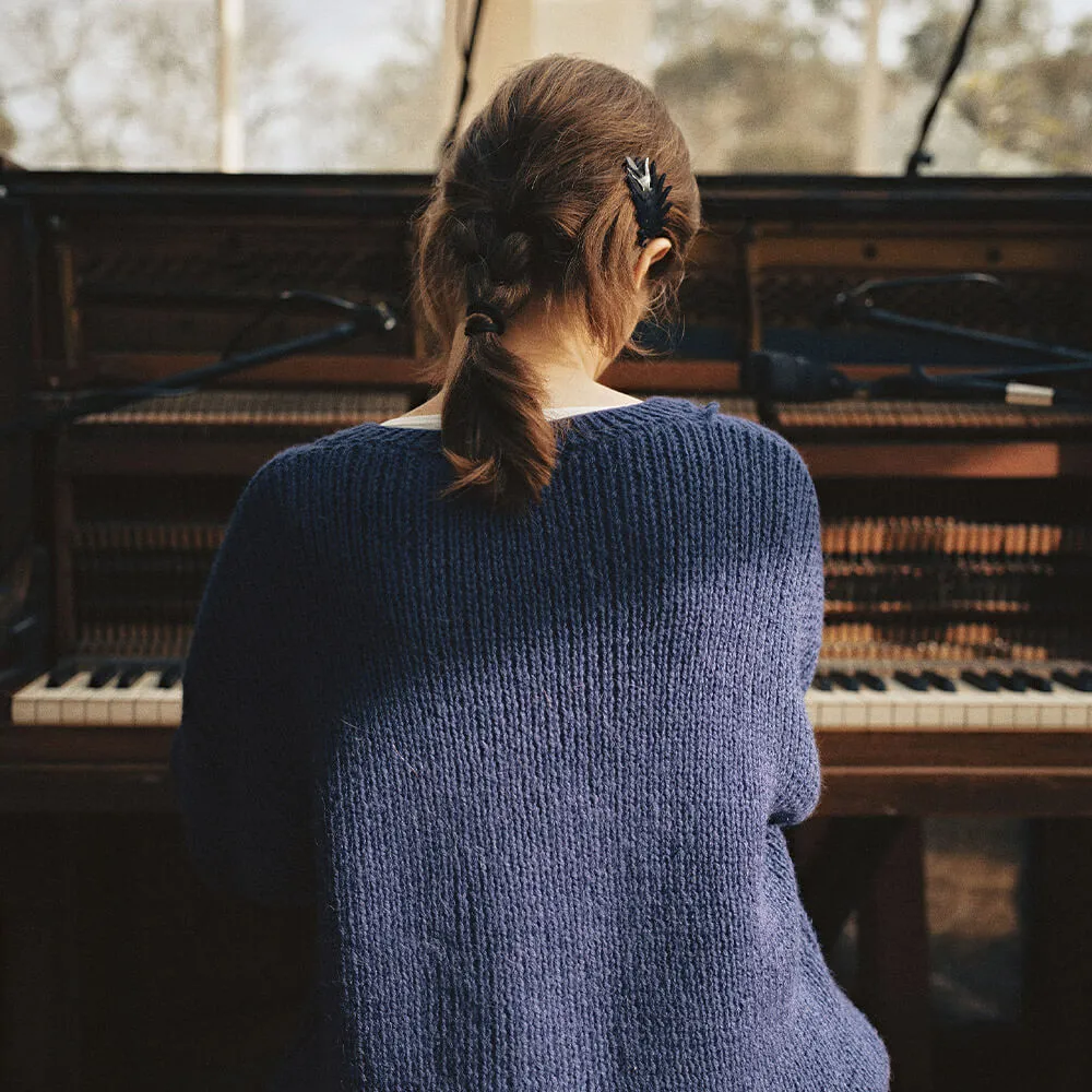 Woman in blue jumper playing piano
