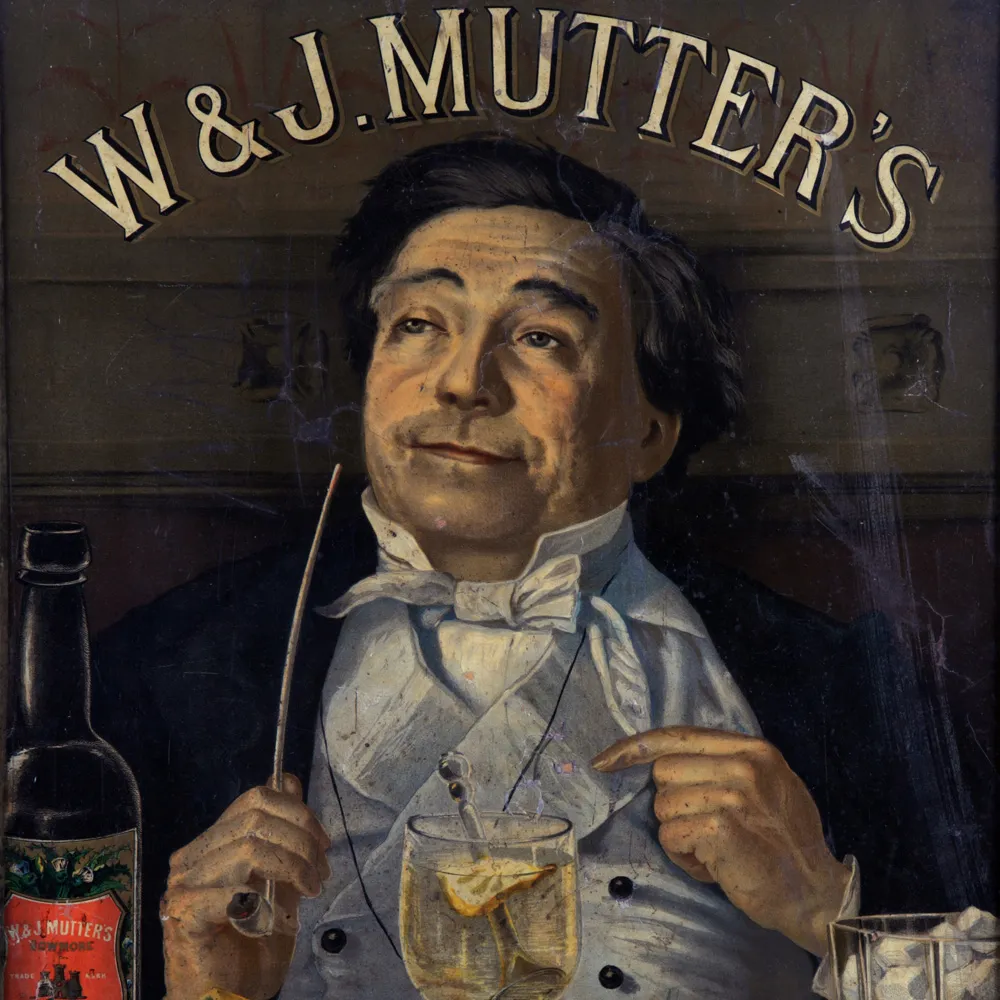 Man in formal dress beneath W&J Mutters-sign