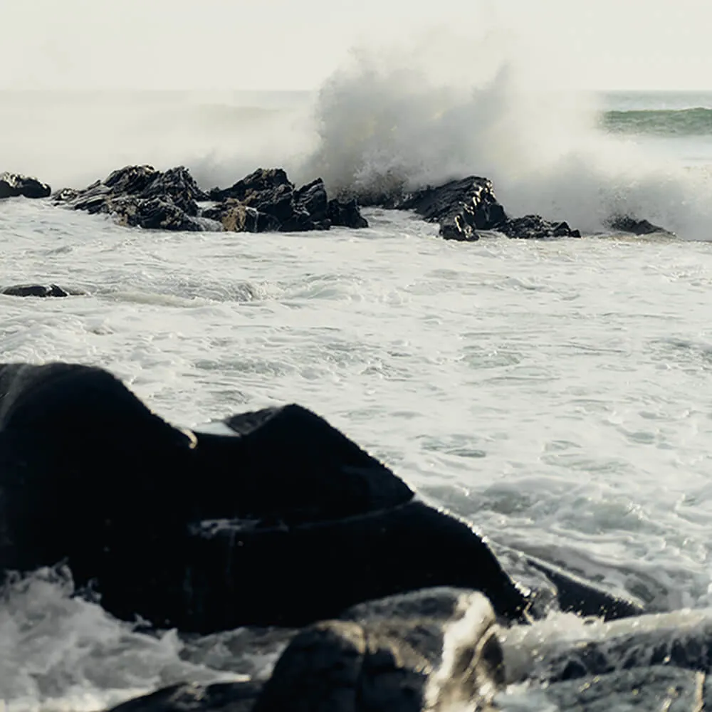 Frothing Islay sea crashing over black rock.
