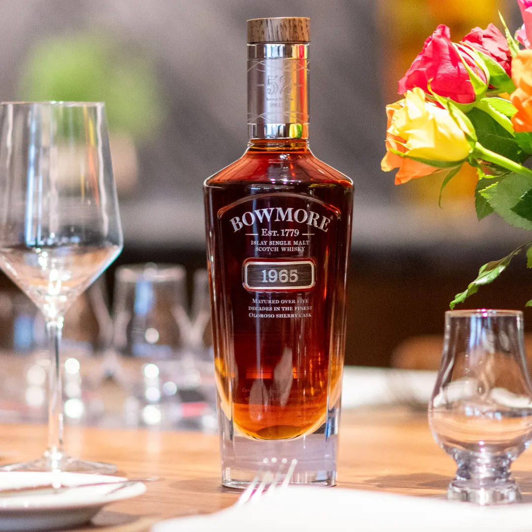 Bowmore 1965 bottle on Machrie dining table surrounded by tableware